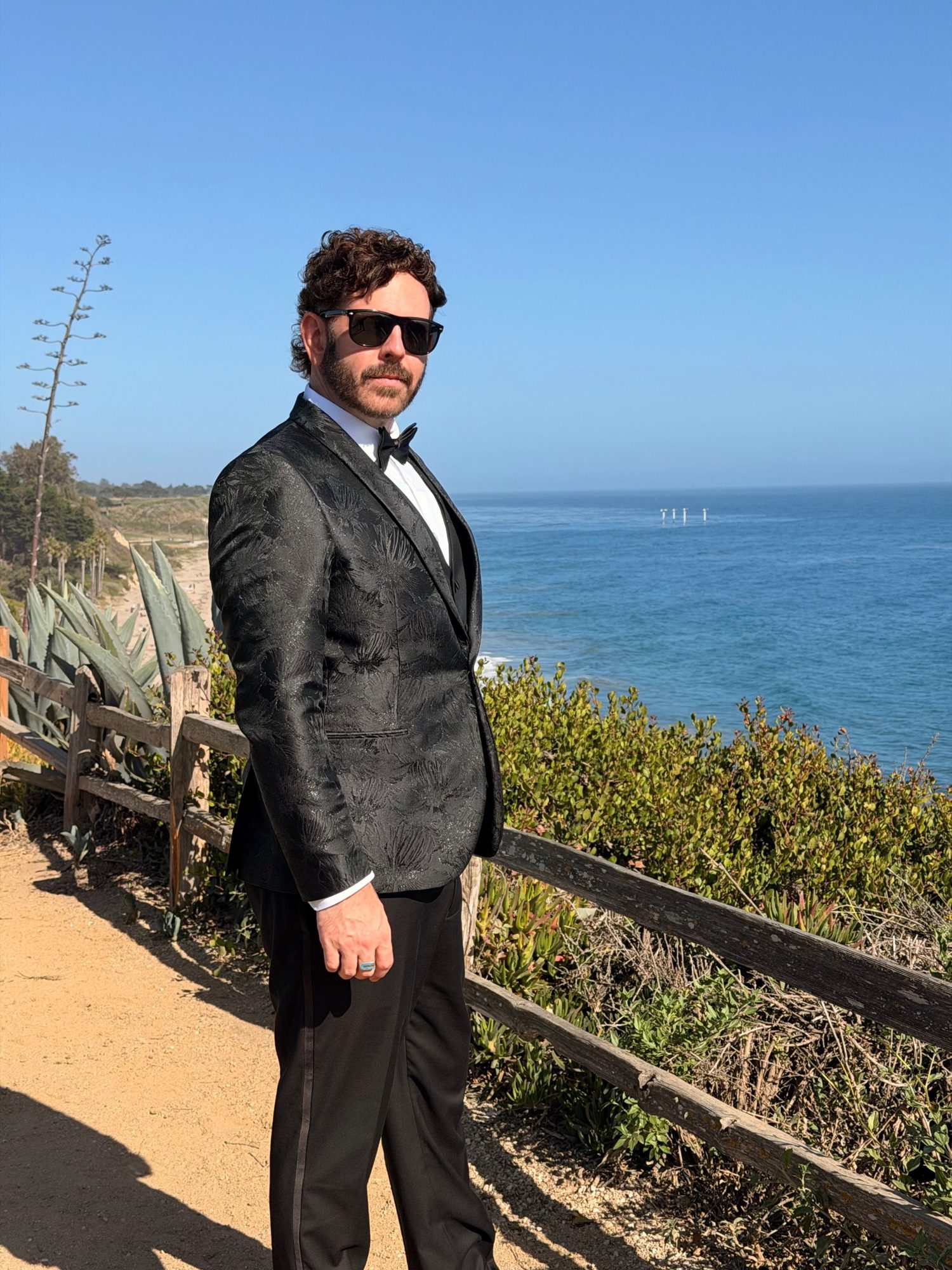 Matt Shockley in a tuxedo on a coastal bluff above the Pacific